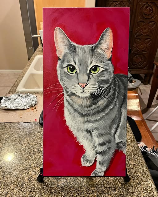 Acrylic painting of a grey tabby cat on a red background, on an easel